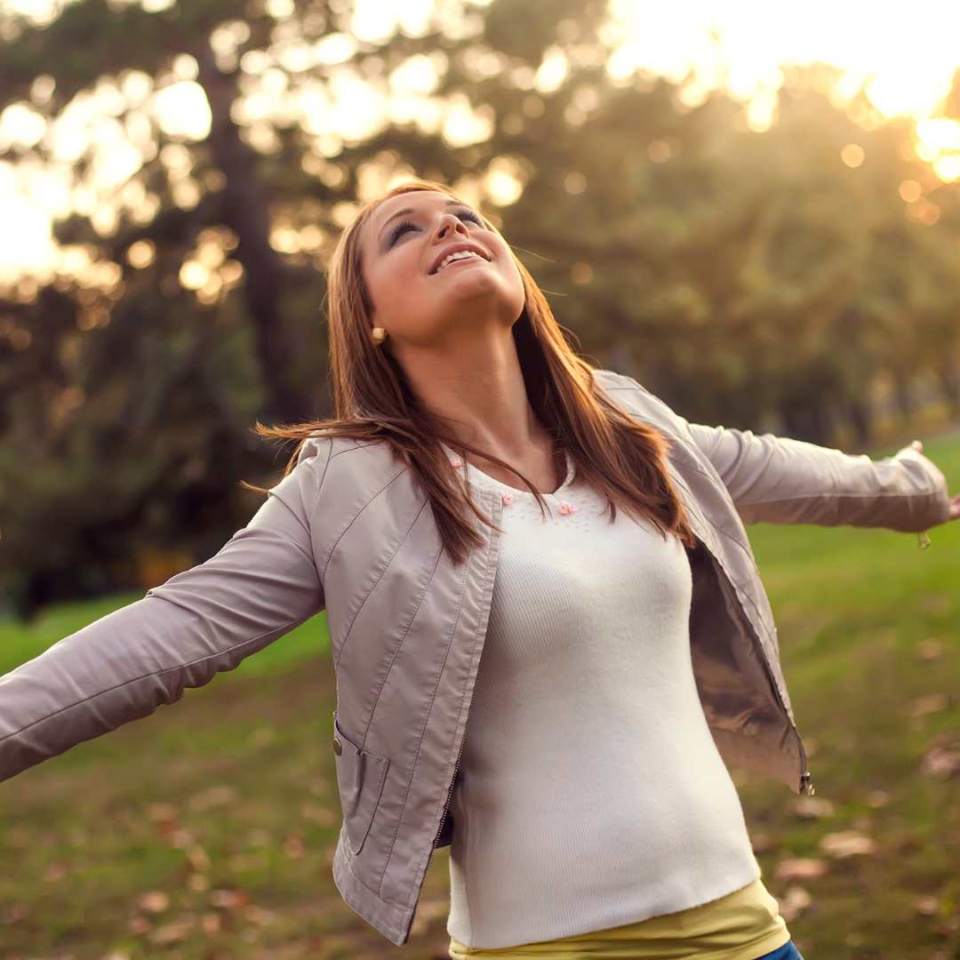 Mujer al aire libre con brazos abiertos mostrando bienestar y energía gracias al ayuno intermitente