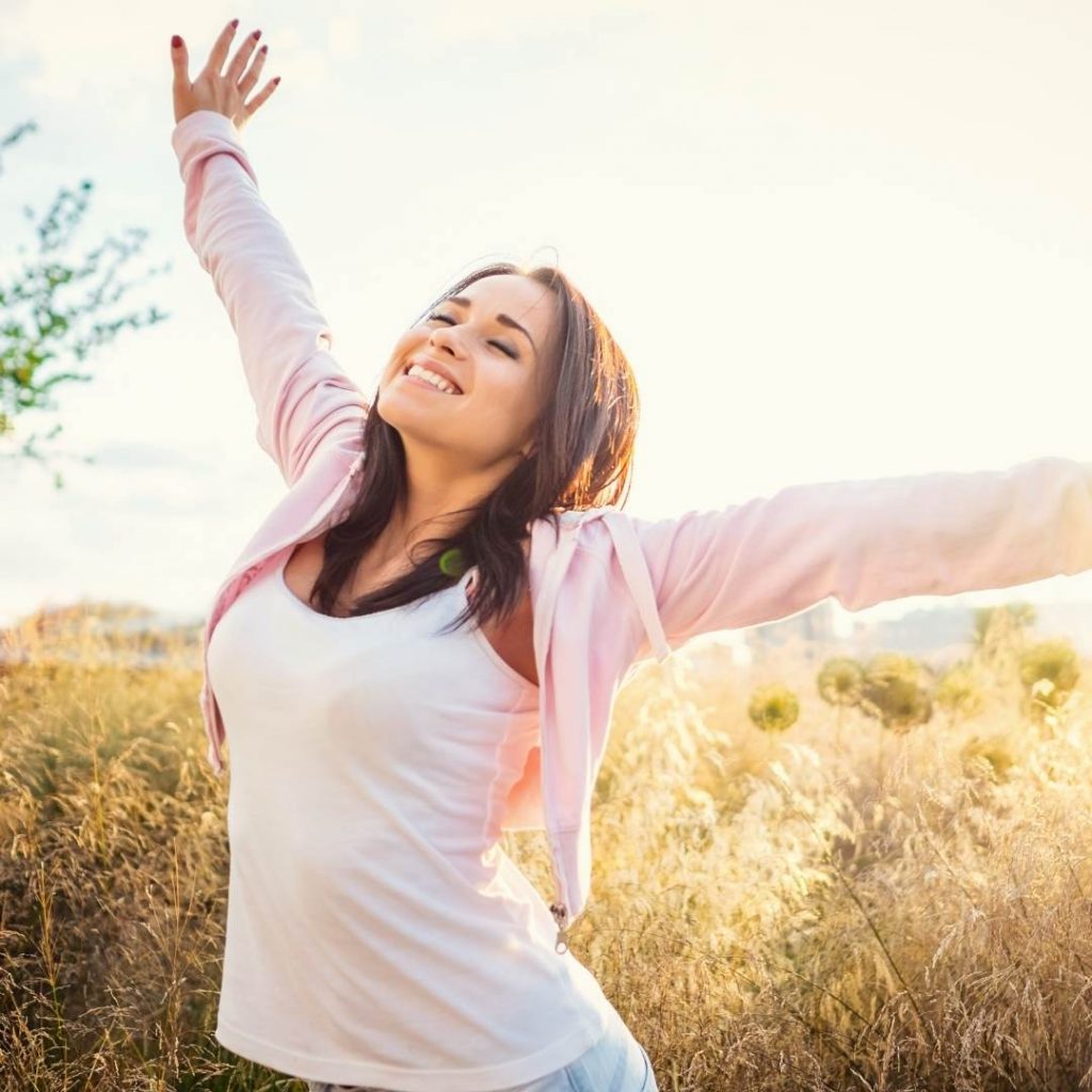 mujer feliz con los brazos abiertos por el campo