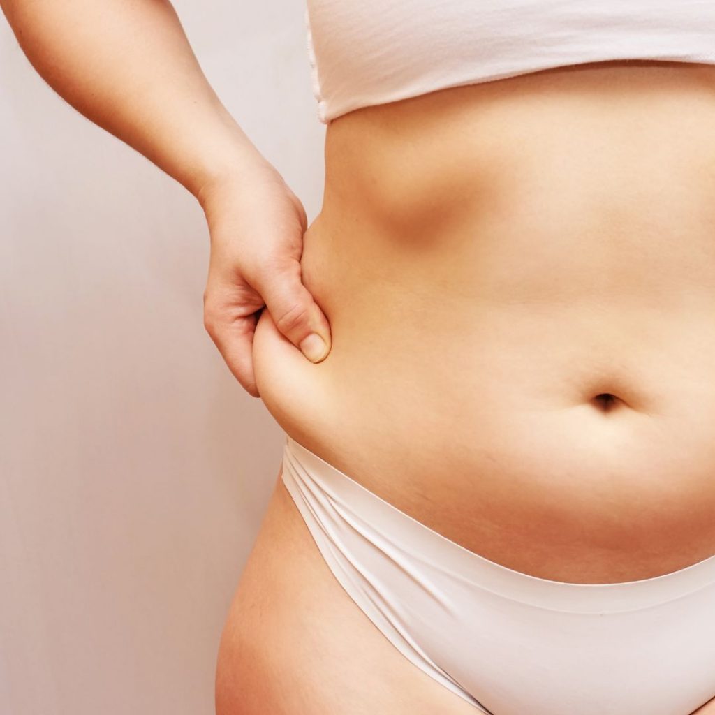 mujer mostrando su exceso de grasa corporal en la cintura