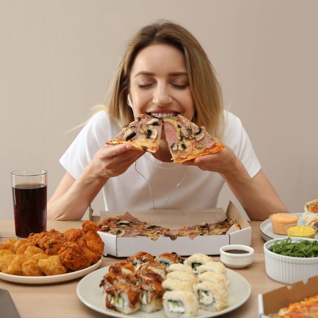 Mujer comiendo pizza y pensando Cómo disfrutar de la comida durante el ayuno intermitente sin culpa ni efecto rebote