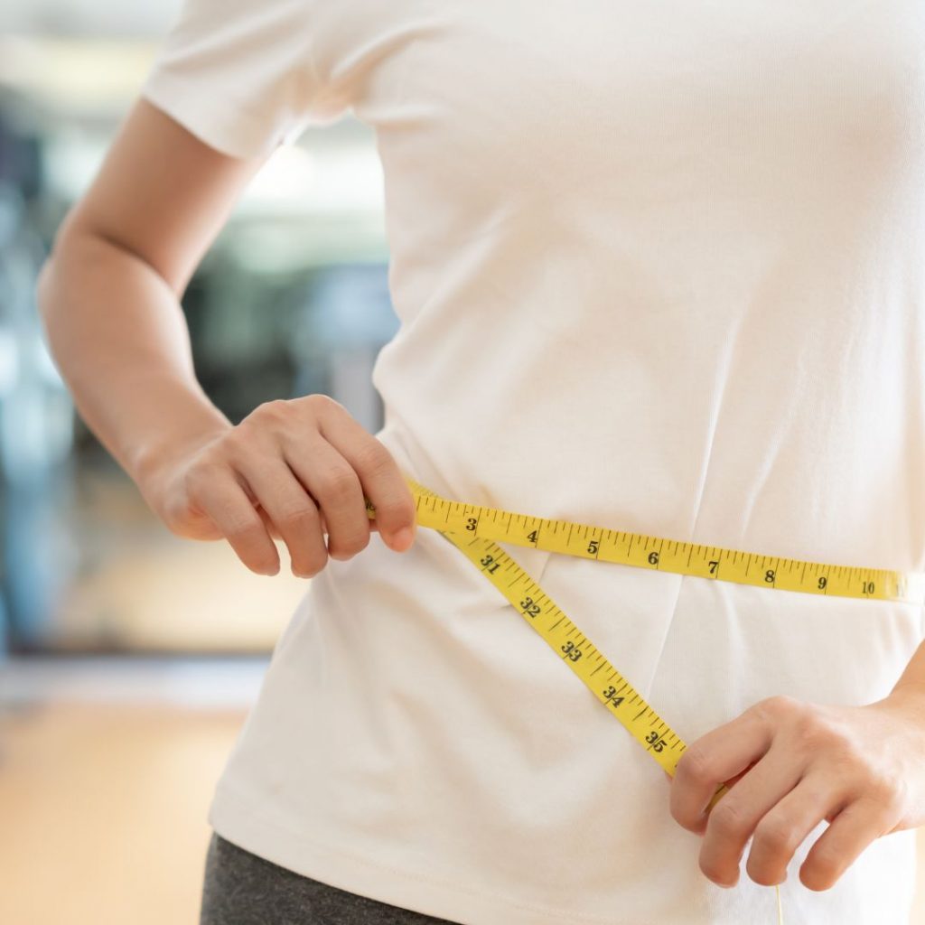 Progreso real de pérdida de peso aplicando correctamente la dieta ayuno intermitente, persona poniendose una cinta en la cintura