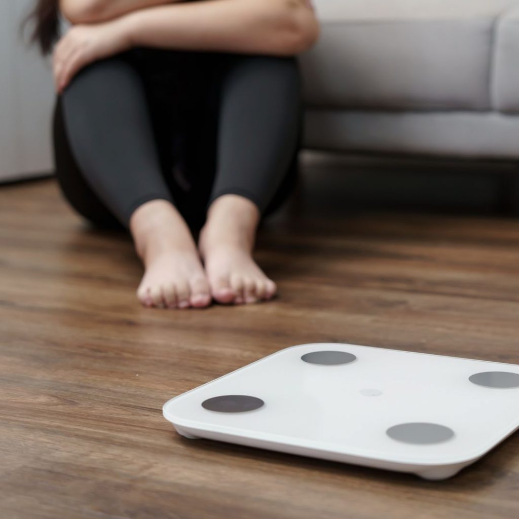 Mujer sentada en el  suelo con Frustración antes de entender en qué consiste realmente el ayuno intermitente